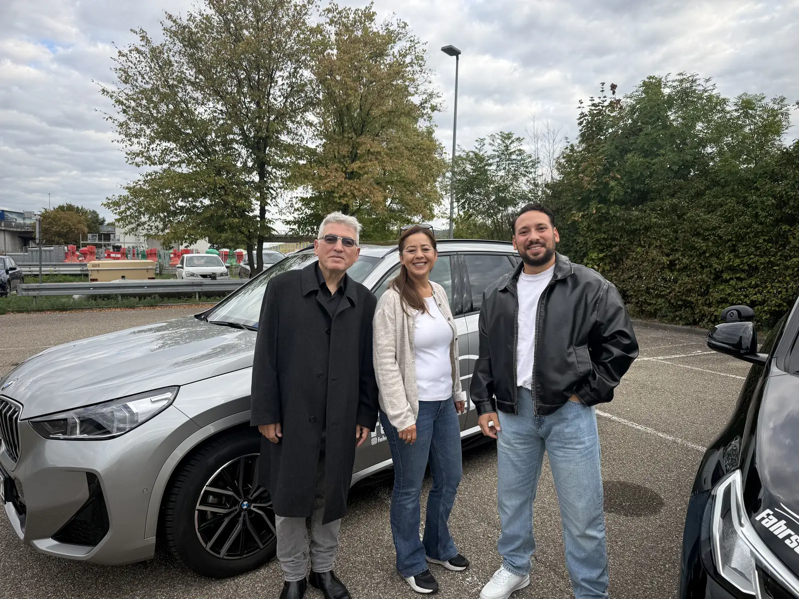 Güray Güldiken, Mümin Sener und Sevim Basli vor einem Fahrschulauto